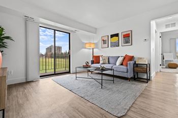 A living room with a grey sofa and a glass table.